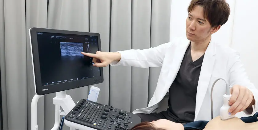 医師が超音波診断装置を使って、患者の胸部をエコーで検査している